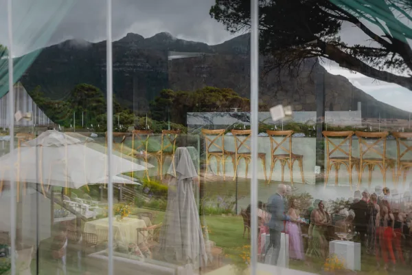 Wedding reception setup with an outdoor wedding reception long banquet table, cross back chairs, and teal drapery with mountain views beyond.