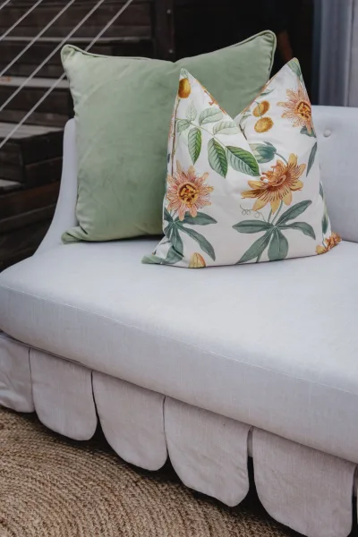 Lounge seating decor in a wedding lounge area with an upholstered sofa, floral throw pillow accent, woven rug, and wood stairs behind