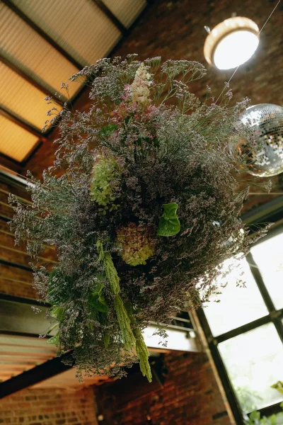 Hanging floral installation styled as a floral cloud installation with hydrangeas, suspended against exposed brick and steel beams.