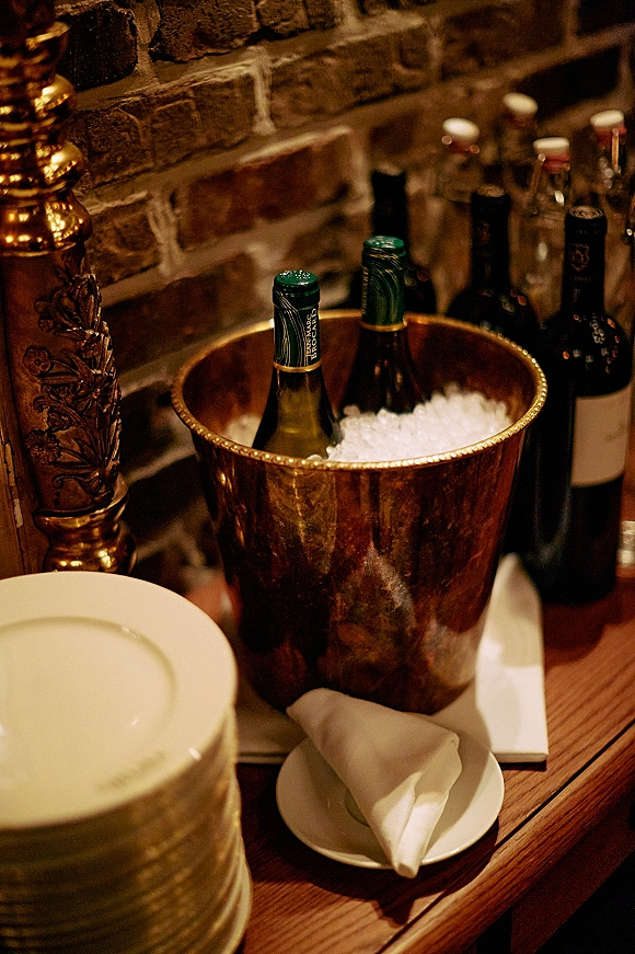 Wine bucket champagne bucket display with wine bottles on ice in a copper ice bucket on a wooden bar against a brick wall backdrop
