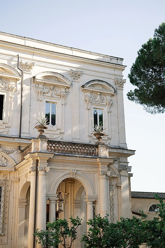Wedding venue exterior with historic wedding venue charm, featuring stone columns and an arched doorway with hanging lantern under blue sky