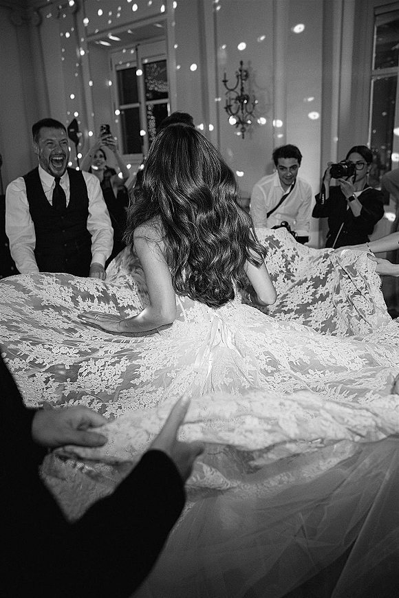 Wedding reception dancing as the bride twirls in a lace dress and long veil, guests cheering in a ballroom with disco light spots