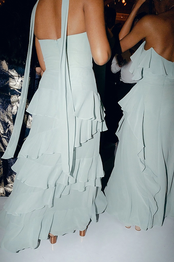 Bridesmaid dresses in tiered ruffle styles with spaghetti straps and long ribbon ties, paired with nude heels on a lively dance floor
