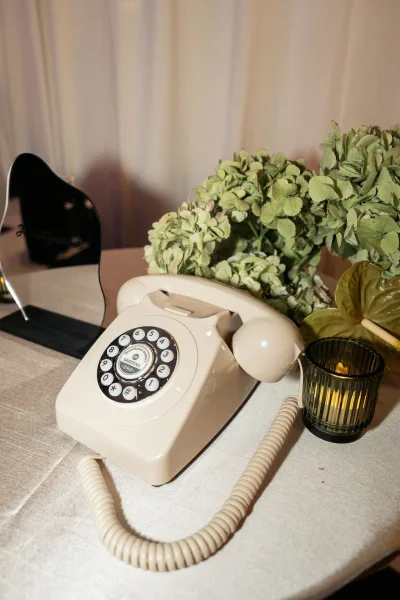 Vintage wedding guestbook with audio guestbook phone on a tabletop, styled with hydrangea flowers and a vinyl record sign against a white paneled wall