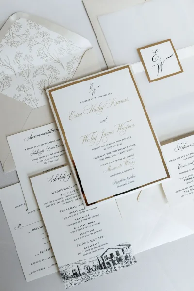 Wedding invitation suite featuring gold foil wedding invitations with a vellum wrap, arranged on white linen for a clean, refined presentation.