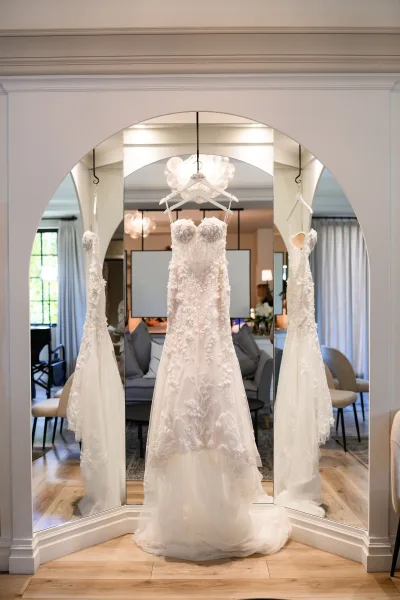 Wedding dress, a floral wedding dress with 3D appliques, corset sweetheart bodice, and tulle train, hanging from a bridal hanger.