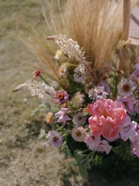 Wedding florals with peony wedding flowers, pastel wildflowers and pampas grass arranged low on a grass lawn in soft outdoor light