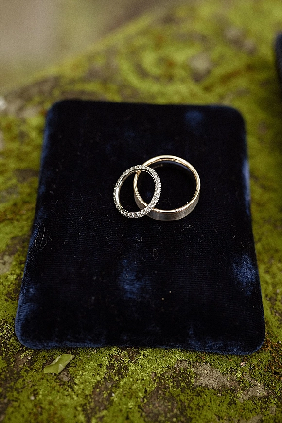 Wedding rings in a wedding ring flat lay, featuring a diamond band and gold band in a velvet ring box on moss and stone surface
