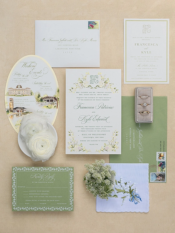 Wedding invitation suite with sage green wedding invitations, calligraphy envelopes, wax seal, stamps, rings, and ranunculus on linen