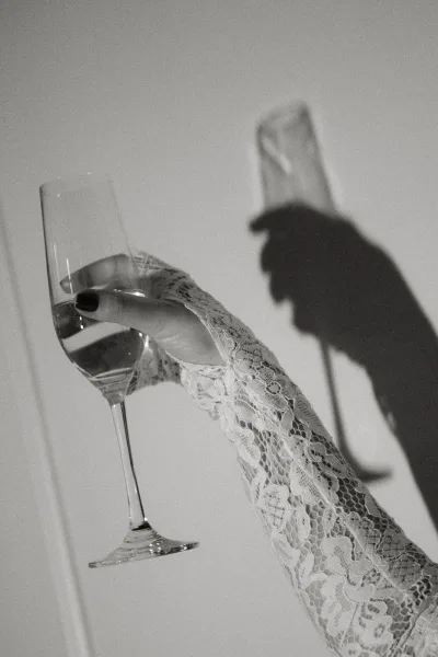 Champagne toast with a raised champagne glass, captured close-up in a hand with a delicate lace sleeve, highlighting elegant festive detail.