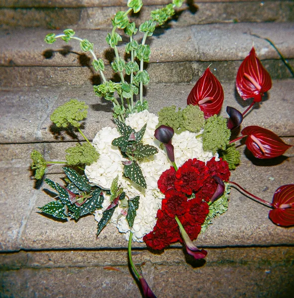 Wedding bouquet in red and white with white hydrangea, red anthurium, calla lilies, and greenery on wooden floorboards