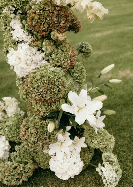 Wedding floral installation with white lily accents in a sculptural, organic design, a modern green-and-white statement arrangement.