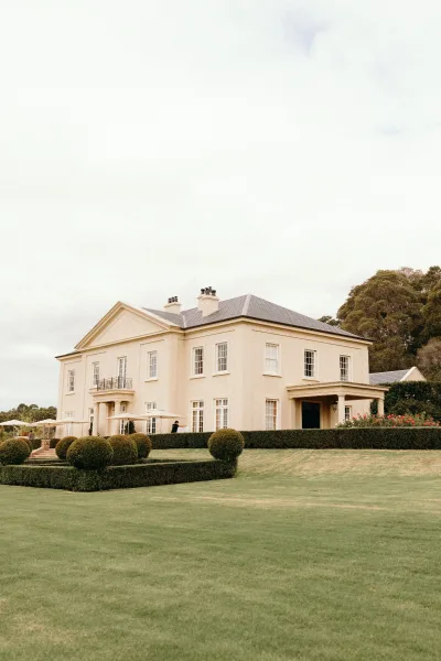 Estate wedding venue with a grand mansion facade and sculpted topiary, offering formal garden charm for elegant outdoor celebrations.