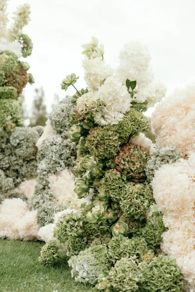 Wedding floral installation with ceremony aisle flowers, lush hydrangeas arranged in low, meadow-style clusters that naturally frame the aisle.