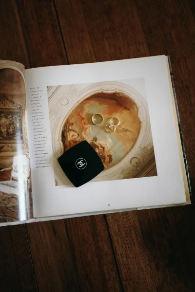 Wedding rings in a ring flat lay arranged on an art book, with an engagement ring nestled among bands in a clean, minimal composition.