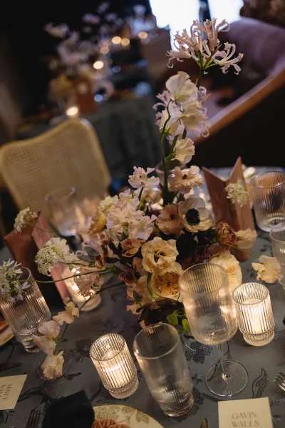 Reception tablescape set as a candlelit wedding table, highlighted by ribbed glassware catching the warm glow for an intimate dinner setting.