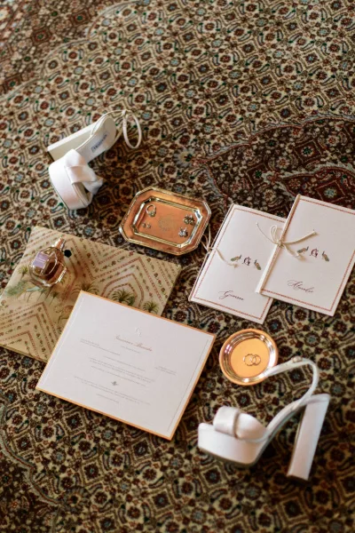 Wedding details flat lay featuring an elegant invitation suite with vow books styled on a patterned rug for a refined look