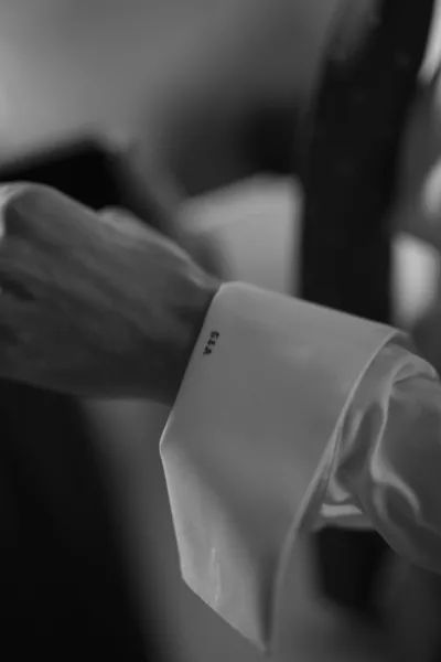 Monogram shirt cuff showcased as a groom cuff detail, with initials on a crisp white sleeve and a coordinating tie in view.