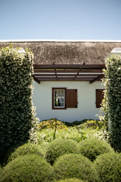 Venue exterior at a garden wedding venue showcasing a vine-covered pergola and cottage-style charm under a clear blue sky