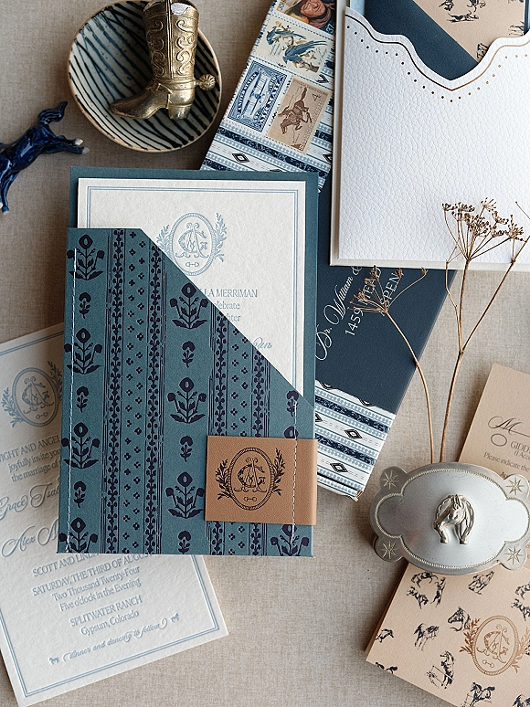 Invitation suite with letterpress wedding invitations, monogram crest, wax seal, vintage stamps and dried flowers on linen flat lay