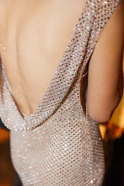 Wedding dress detail on a beaded wedding dress with crystal and rhinestone sparkle, spaghetti straps and plunging neckline in soft indoor light