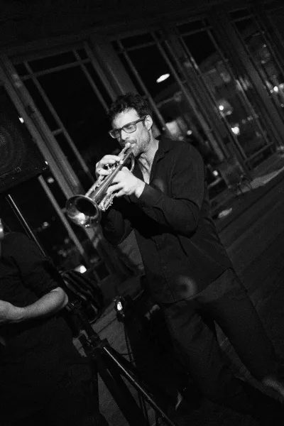Wedding band performance fills the room with live wedding music, a trumpet gleaming near windows with night lights in an indoor venue.