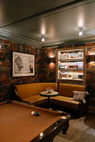 Lounge seating decor anchors a banquette seating nook with a leather banquette, set against patterned wallpaper and built-in shelves.
