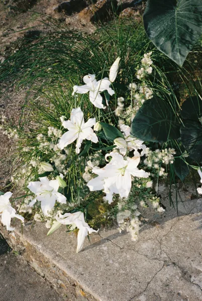 Staircase flowers sweep up stone steps in a staircase wedding flowers display with white lilies framed by dry soil and rocks.