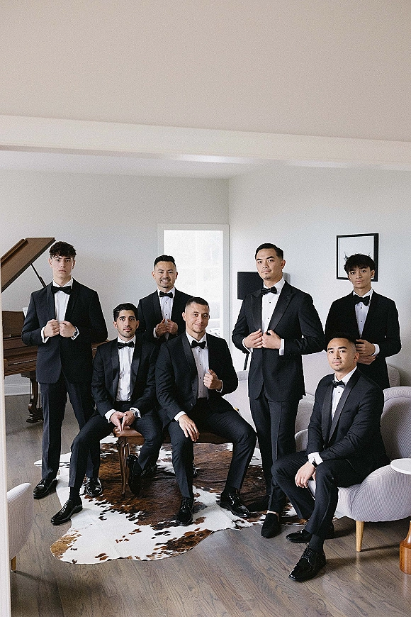 Groomsmen portrait of a wedding party in groomsmen tuxedos, sitting and standing in a living room with piano and window light