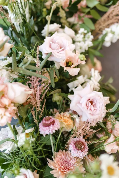 Bridal bouquet with blush rose bouquet tones, featuring peach blooms, pink chrysanthemums, eucalyptus and astilbe against soft blurred florals