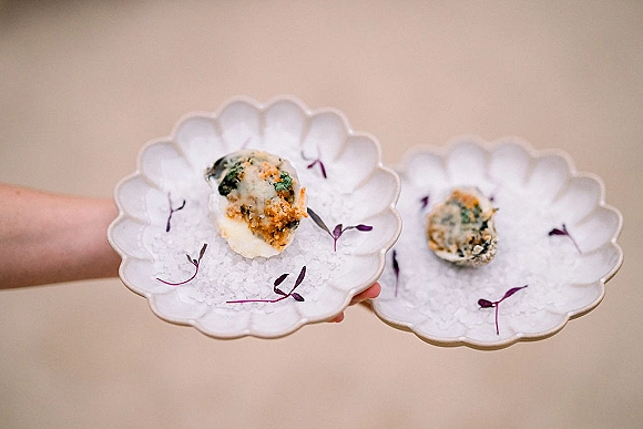 Wedding hors d'oeuvres and passed wedding appetizers on scalloped ceramic plates over crushed ice, garnished with microgreens in held hands