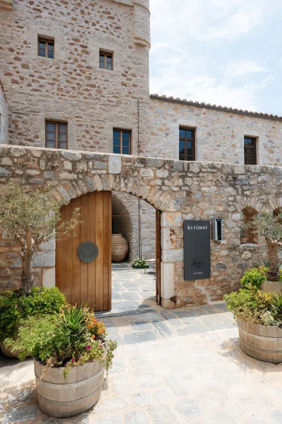Wedding venue exterior of a rustic stone venue framed by an open wooden gate, overlooking a cobblestone courtyard and weathered stone facade.