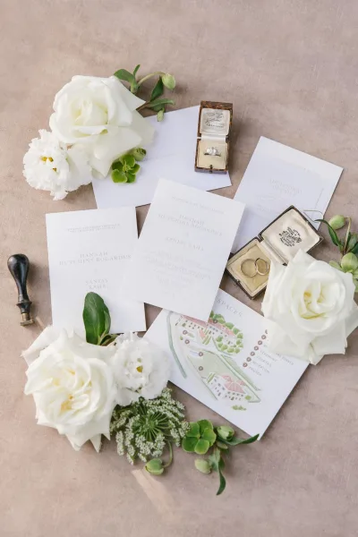 Invitation suite wedding invitation flat lay with RSVP and details cards, wax seal envelope, rings, white roses and greenery on linen backdrop