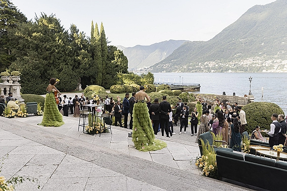 Cocktail hour entertainment with string musicians in green ruffle dresses playing on a stone terrace overlooking a lake and mountains