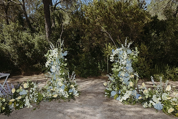 Wedding ceremony backdrop with outdoor ceremony flowers, lush hydrangeas and greenery arranged along a forest garden path