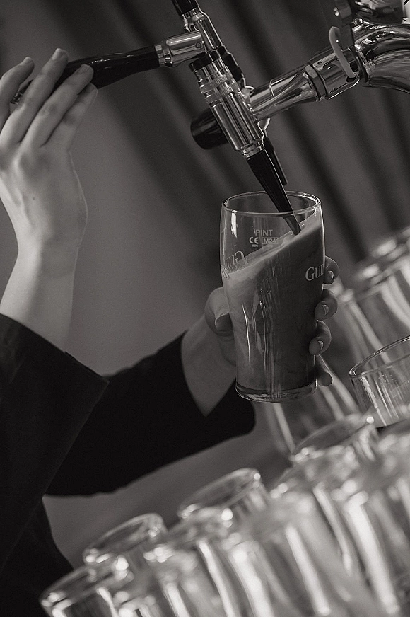 Wedding bar service with a beer tap pouring draft beer into a pint glass on the bar counter in an indoor reception bar area