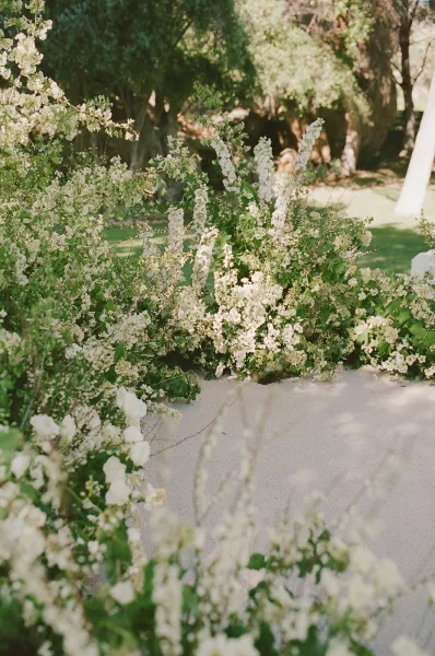 Ceremony aisle design for an outdoor ceremony aisle, lined with florals amid garden trees on a soft grass lawn.