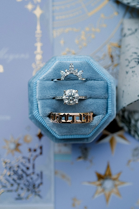 Wedding rings in a ring stack photo featuring an engagement diamond and chevron band on patterned stationery with star motifs, in a velvet ring box