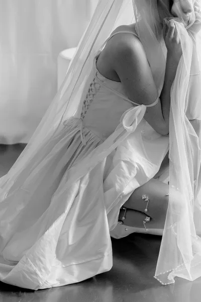 Bridal portrait of a bride with veil draped over her face, the beaded edge catching light for an elegant, modern bridal look