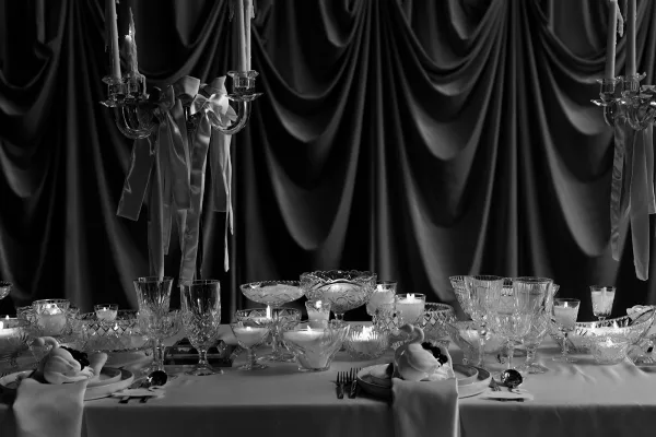 Reception tablescape styled as a candlelit wedding table, featuring a gleaming candelabra before a softly draped fabric backdrop.