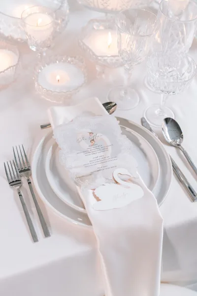 Wedding place setting with a vellum wedding menu layered on a satin napkin, elegant typography and subtle translucence highlighting the details