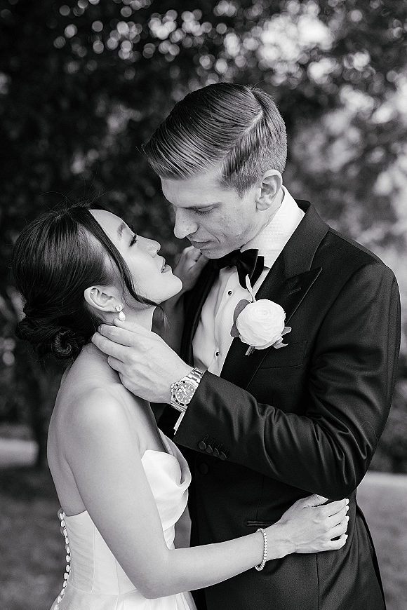 Couple portrait in a black and white wedding portrait, bride and groom embrace with forehead touch in a lush garden backdrop