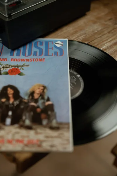 Vinyl record player on a wood table with a black vinyl record and record sleeve, a retro wedding cocktail hour music setup