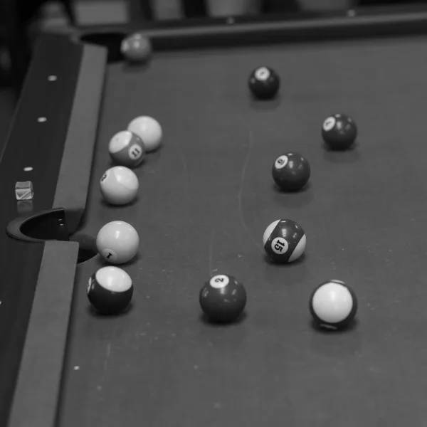 Pool table detail with billiard balls close up on felt by the corner pocket, showing rails and texture in a game room interior
