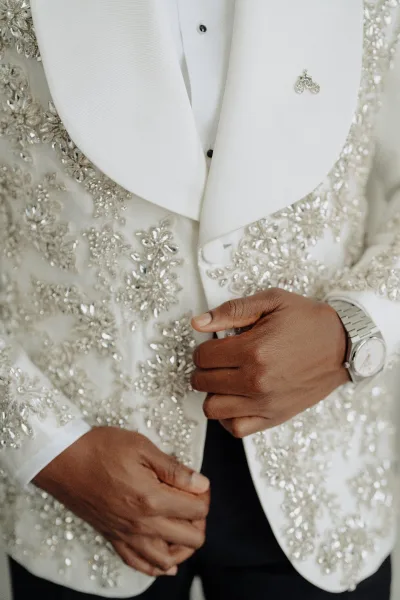 Groom tuxedo with a beaded tuxedo jacket as he buttons the front, highlighted by a sleek shawl lapel and refined tailoring.