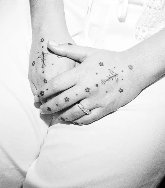Wedding ring close-up highlighting bridal ring detail on tattooed hands, the band catching light as fingers rest gently together