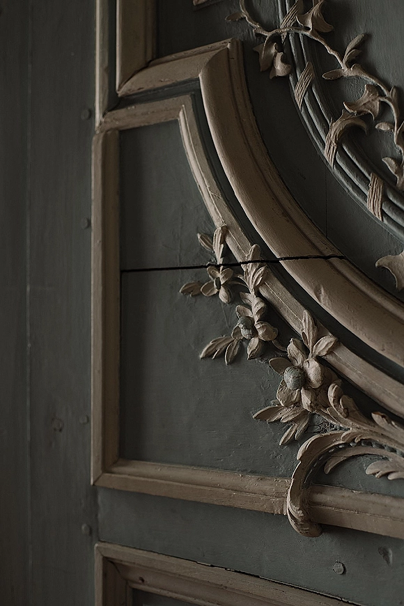 Ornate wall molding on antique wall paneling with carved floral appliques and decorative trim over painted wall panels