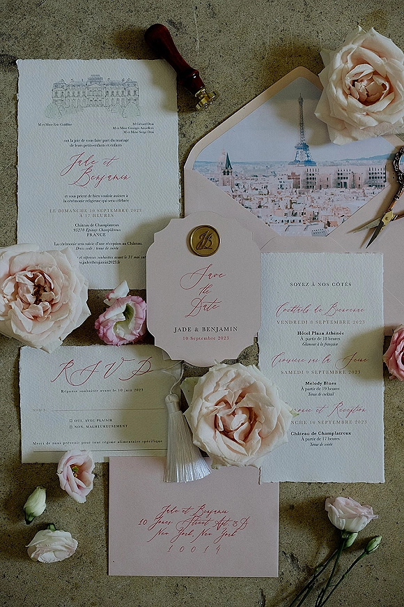 Invitation suite wedding invitation flat lay with blush roses, wax seal, ribbon tassel, vintage key and scissors on stone surface