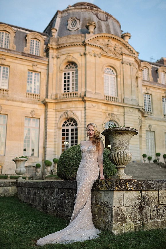 Bridal portrait in a sequin wedding dress, bride in a long sleeve sparkly gown with train by a historic stone balustrade and topiary shrubs