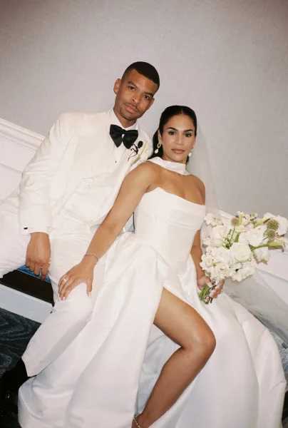 Couple portrait of bride and groom seated pose on a carpeted staircase, bride holding white bouquet in strapless dress and veil